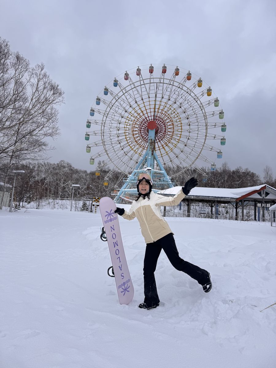 手稻 Olympia 區,單板學員拿著雪板站在大觀覽車前